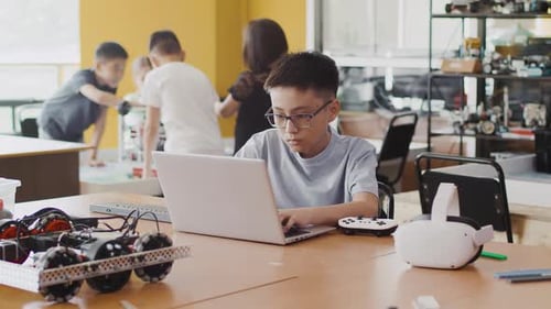 Schoolboy Working on a Laptop in a Class at a Robotics Lesson and Thinking About Coding for a VR