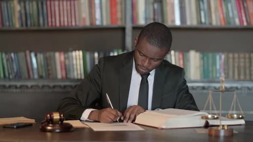 Pensive African Male Lawyer Writing Legal Documents in Office