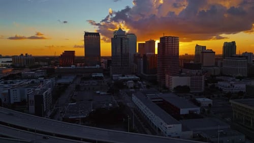 Aterrissagem aérea filmada no horizonte da cidade de Tampa, com uma rodovia e tráfego intenso como o sol.