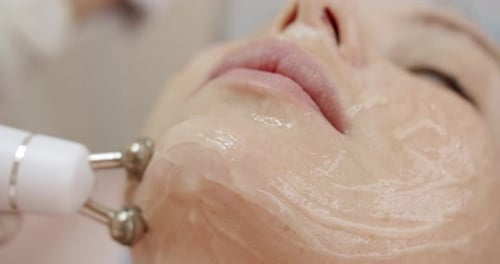 Closeup of Cosmetologist Doing Facial Microcurrent Procedure Using Apparatus