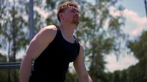 portrait of young sweaty tired fitness athlete or bodybuilder after training outdoors on sports
