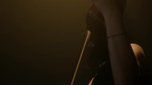 Young Woman Plays Violin in a Dark Room