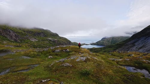 Tourist with a Backpack on Top and Looking at the Landscape on the Way to the Top of Manken Mountain