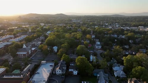 Aerial establishing shot over quaint neighborhood of america at sunset. Housing area with homes and