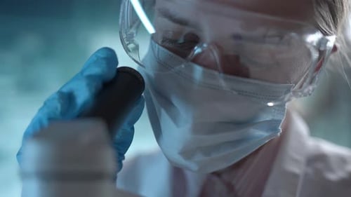 Laboratório de Ciências Médicas Um microbiologista usando óculos está examinando uma análise microscópica