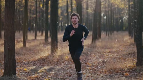 Closeup Shot of a Man with Curly Hair in a Black Sports Uniform Running Quickly During His Morning