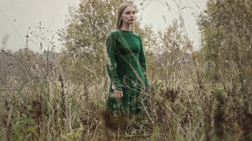 Model posing in a field wearing green dress