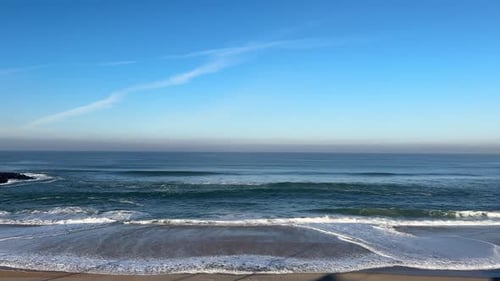 Waves and backwash from the sea on a beautiful blue sky day on a sandy beach.