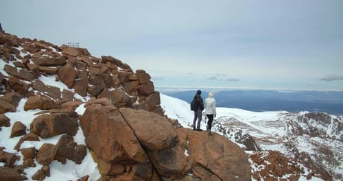 Couple on Rocks High Above Rocky Mountains, Dangerous Hike Adventure
