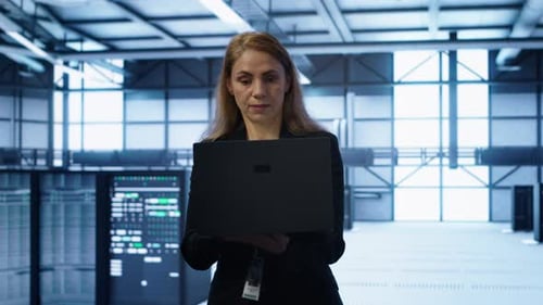Software Developer Walking in Data Center with Laptop