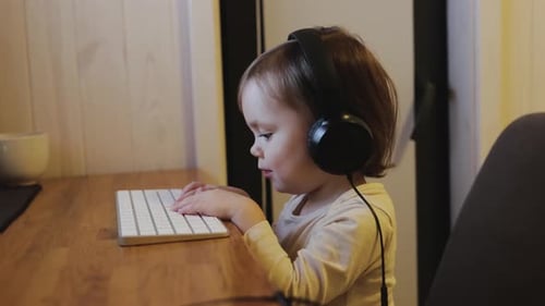 Toddler Interacting With Wireless Keyboard Wearing Headphones