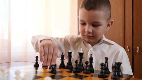 L18. A boy makes a move while playing chess. Leisure games.