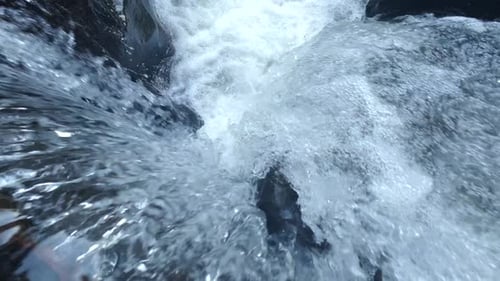 Primer plano del agua en cascada que fluye río abajo en cámara lenta