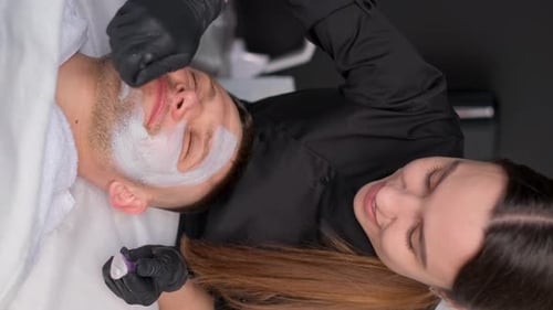 Woman Applies Facial Mask to Man at Spa