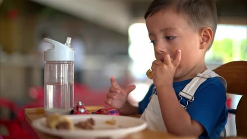 Slow motion close up of a young latin toddler eating a barbacoa taco with his hands in a Mexican res