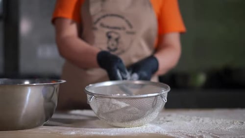 Sifting Flour on Wooden Table in Kitchen