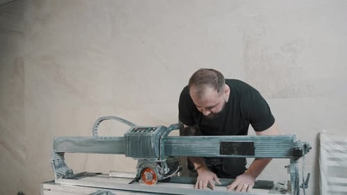 Smooth cutting in slow motion as a man operates a tile saw in a workshop