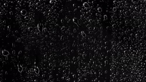 Rain Drops Flowing on Dark Surface Macro Shot