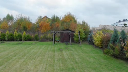 Child's empty swing and a barrow in the backyard.