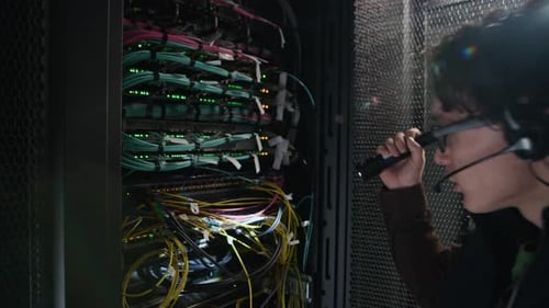 Network Engineer Inspecting Server Rack with Flashlight in Data Center