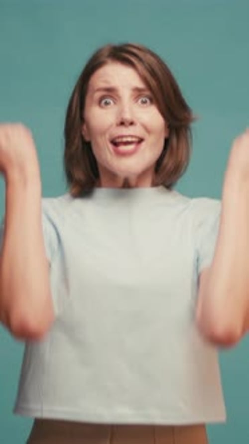 Excited woman cheering with arms raised on blue background