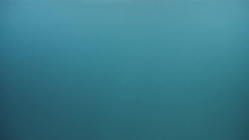 Abstract underwater background of light rays shining through waves and clear sea water.