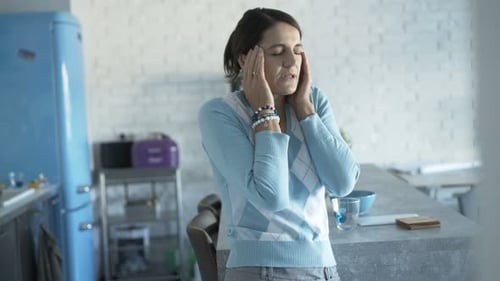 Stressed young woman massaging temple having headache pain at home