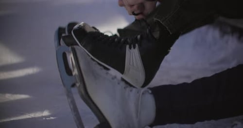 Tying ice skate laces in winter snow