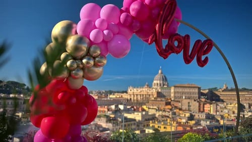 Pink, red and gold, love balloon arch at panoramic view of Vatican City, Rome, Italy.