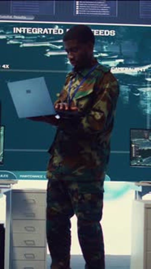 Man in Camouflage Using Laptop in Dark Workplace