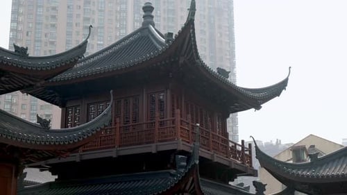A traditional Chinese pavilion stands in stark contrast against a modern high-rise apartment