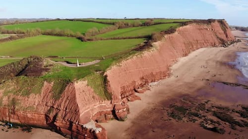 Aerial Of Orcombe Cliffs Coastline In Exmouth With Visitors On Beach On Sunny Day. Dolly Forward