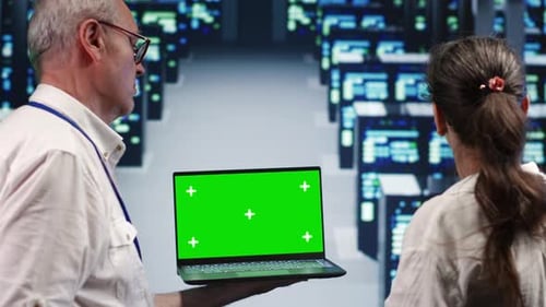 Technicians Holding Laptop with Green Screen in Server Room