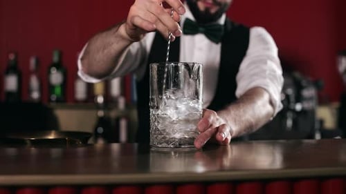 Close Up of Bartender Stirring Cocktail with Ice Cubes