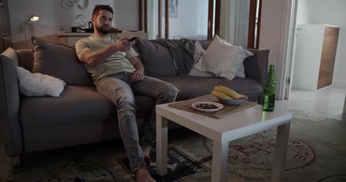 Man Relaxing on Sofa Watching Television at Home