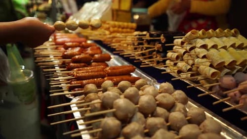 A customer choosing from a variety of meat kebabs food options in a traditional open night market in