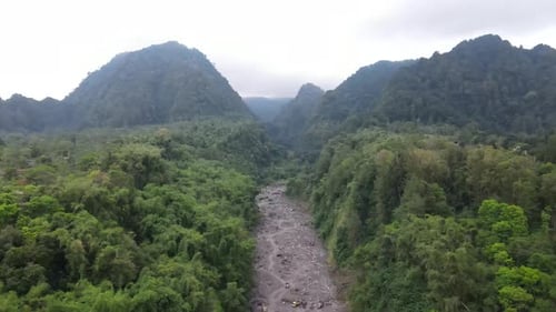 A misty view of Mount Merapi flanked by green hills. Mount Merapi is in Yogyakarta, Indonesia.