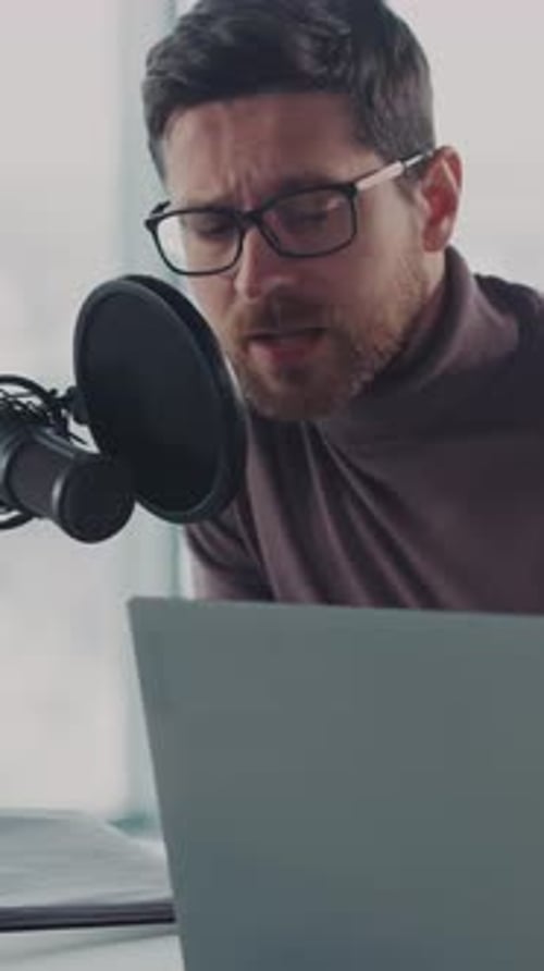 Man Recording Audio Content on Microphone and Laptop