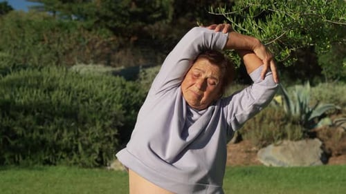 Active Senior Woman Doing Stretching Exercises at Park on Sunny Day