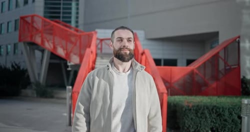 Young Man with Stylish Trendy Hairstyle and Beard in Casual Clothes Walking Down Street in Urban