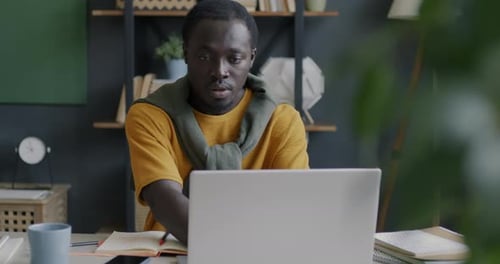 Young African American Entrepreneur Using Laptop Typing and Drinking Coffee in Home Office
