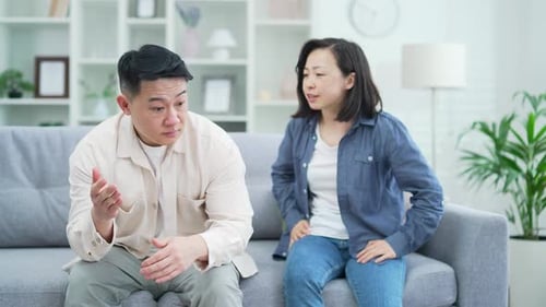 Couple Arguing on Couch in Bright Living Room