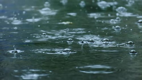 Slow motion of raindrops falling on submerged road in rainy season.