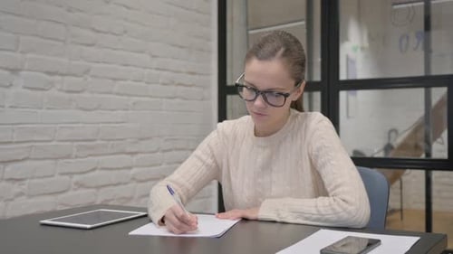 Woman Writing at Desk in Modern Office