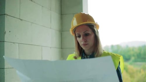 Junge Bauingenieurin beaufsichtigt Baustellenpläne in Innenräumen
