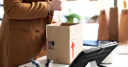 Woman packs a purse in a box