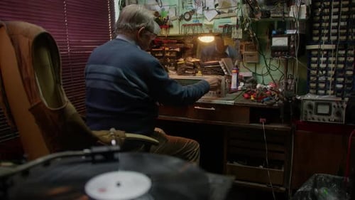 Man Adjusting Radio in Cluttered Workshop