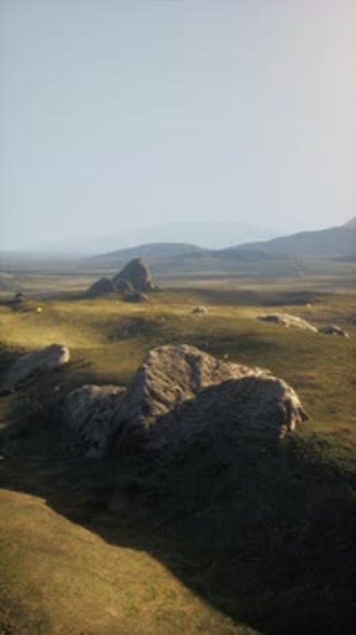 Grassy Field With Rocks and Mountains