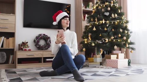 Woman in Santa Hat Using Phone at Christmas