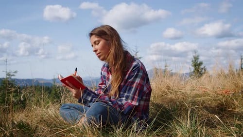 Serious Woman Writing Notes in Summer Field